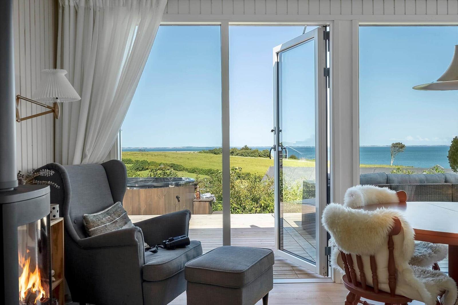 Raum mit Sessel, Kamin und Blick auf das Meer.