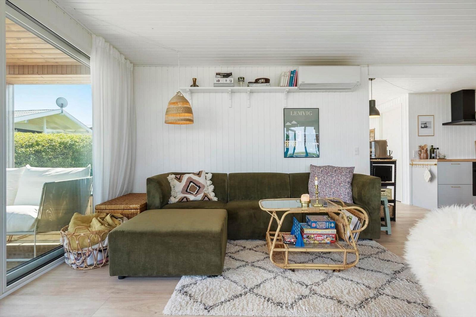 Wohnzimmer mit grünem Sofa, runder Couchtisch und Blick auf Balkon.