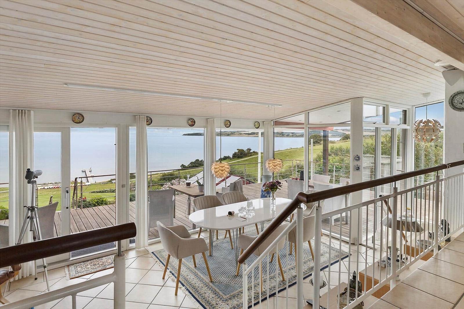 Essbereich mit Blick auf See und Grünflächen durch große Fenster.