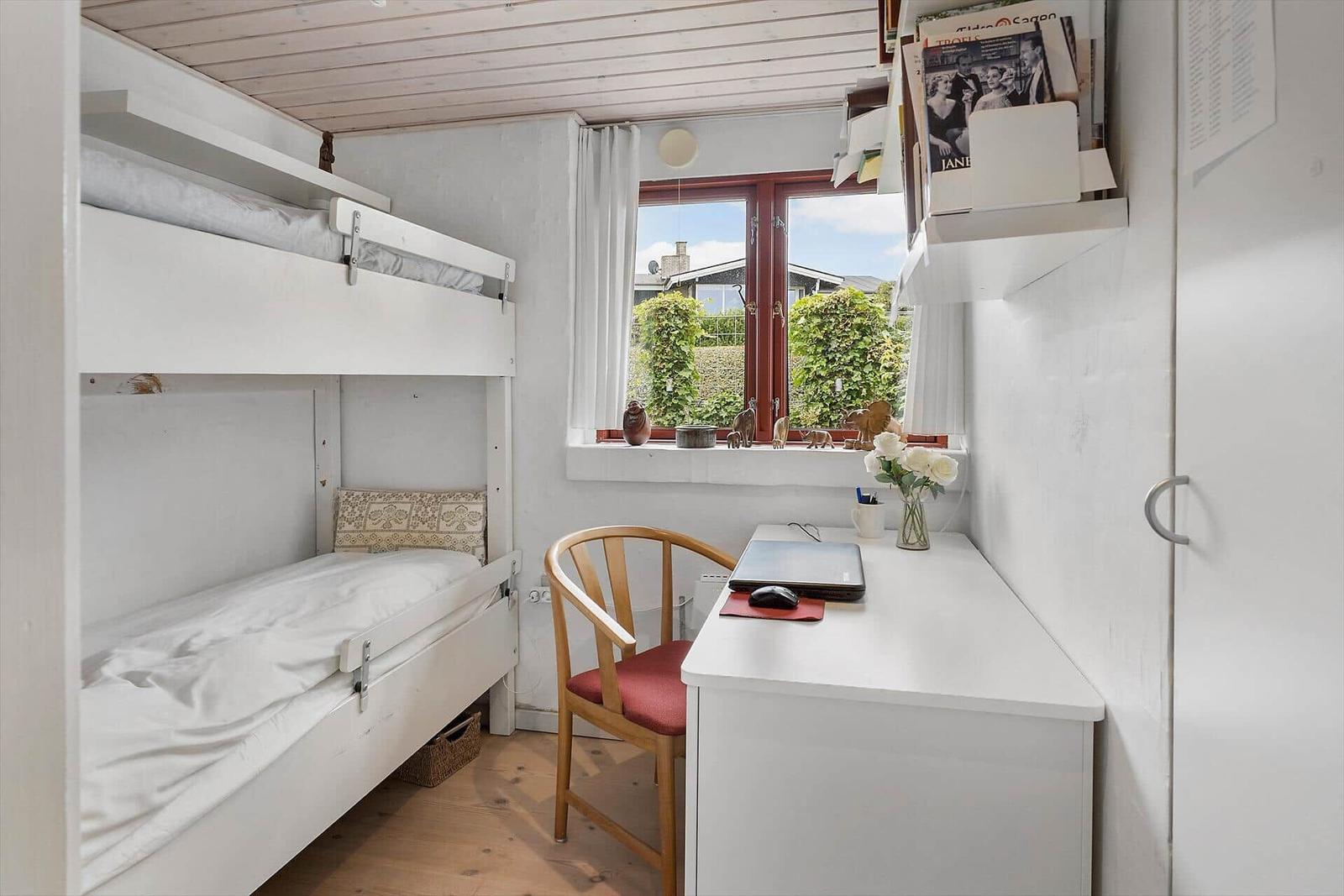 Zimmer mit Doppelstockbett, Schreibtisch und Fenster mit Blick auf Garten.