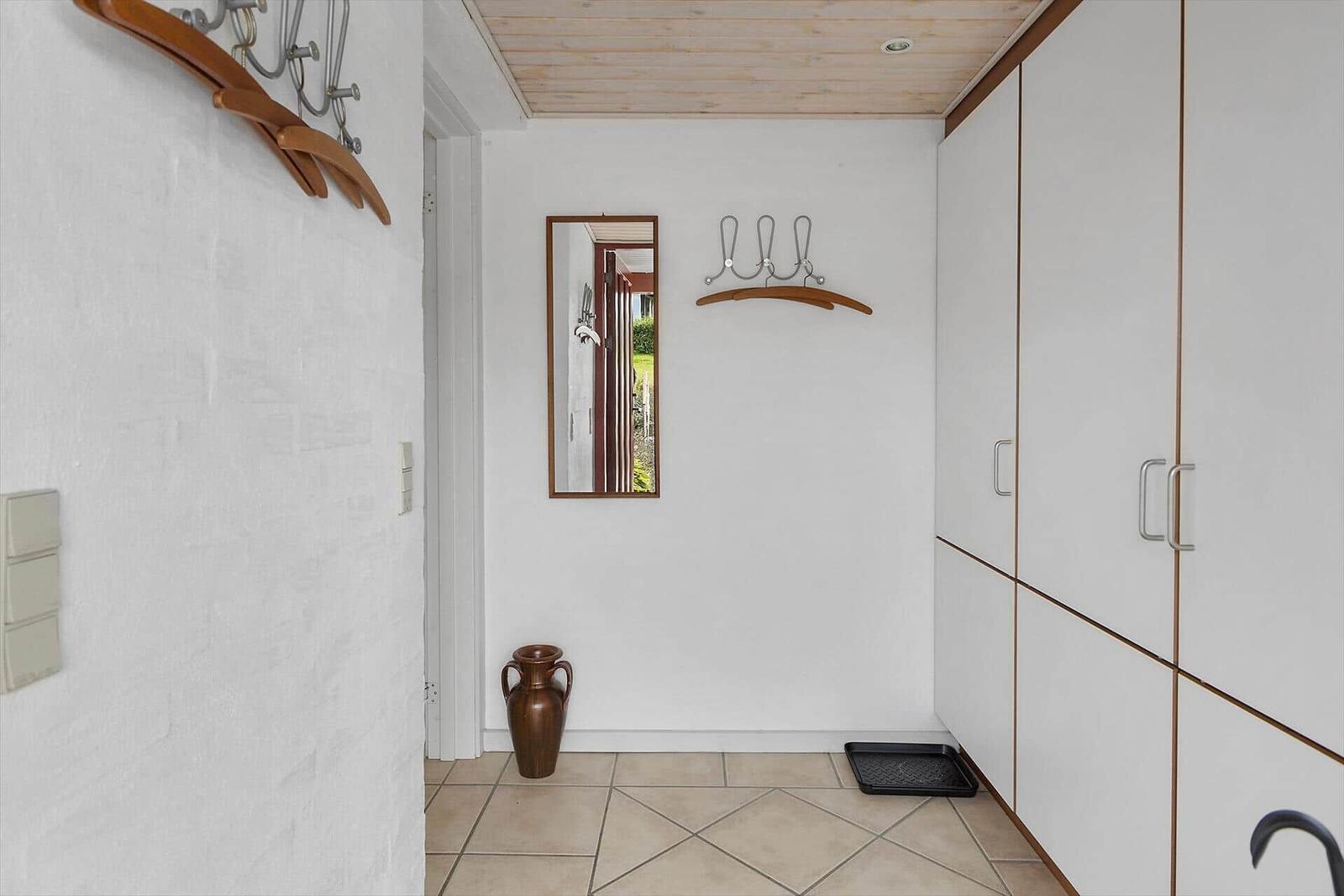 Eingangsbereich mit Garderobe, Spiegel und Fliesenboden.