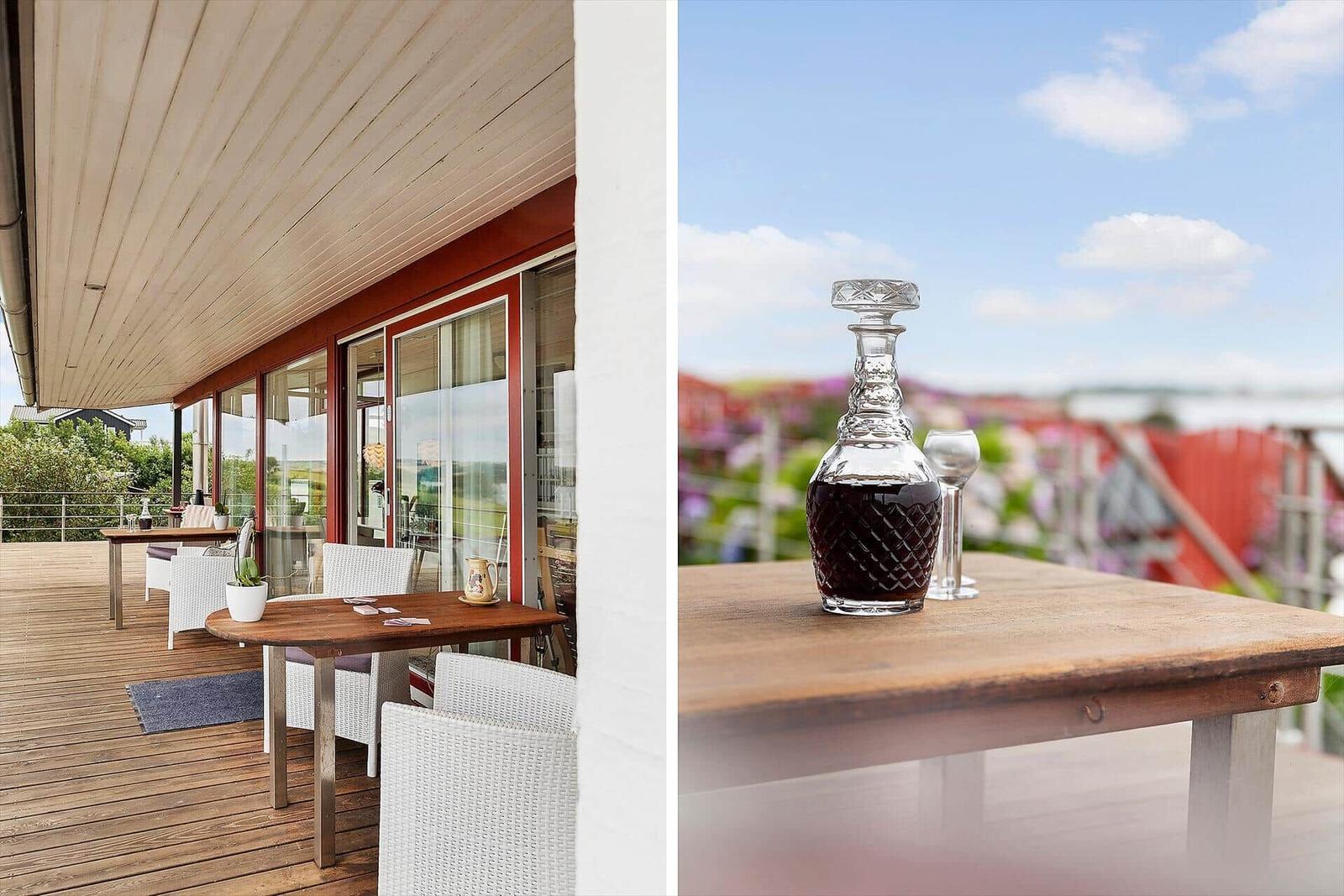 Terrasse mit Tisch und Stühlen, Dekanter mit Wein und Blick auf Landschaft.
