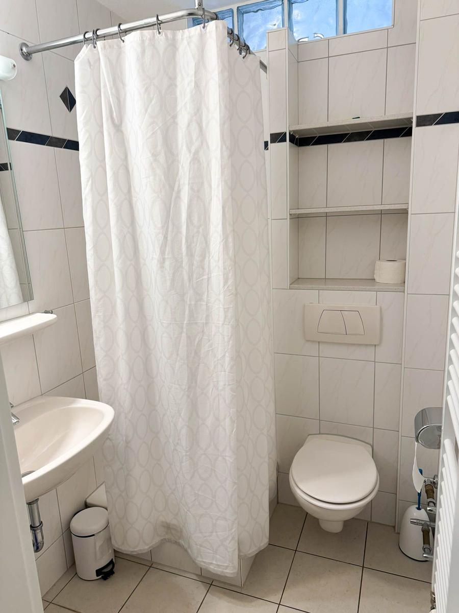 Badezimmer mit Dusche, Toilette und Waschbecken.