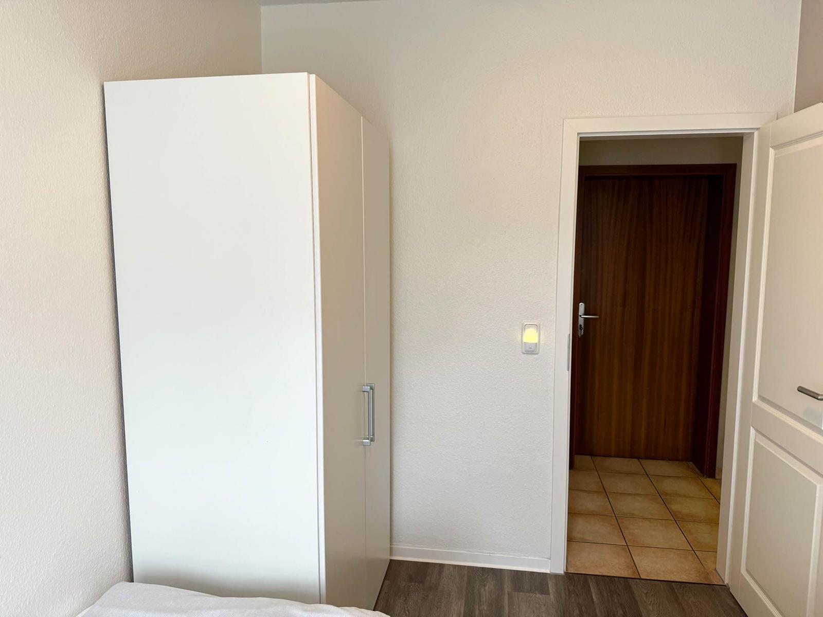 Schlafzimmer mit Kleiderschrank und Tür zum Flur.