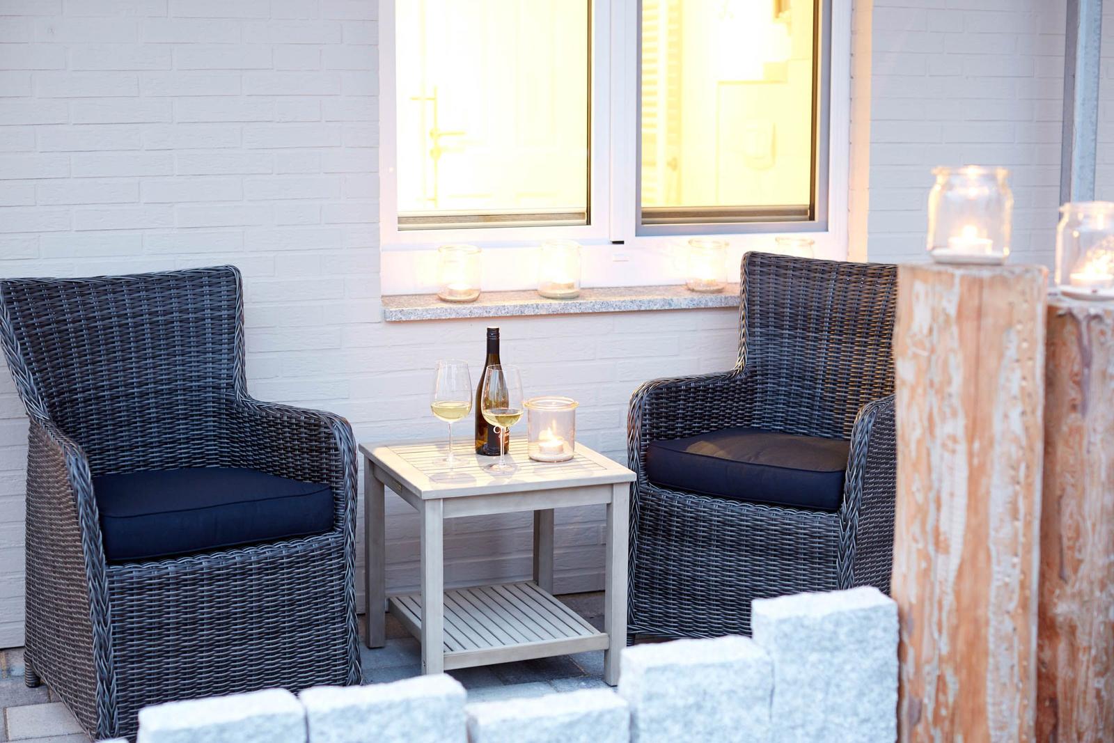 Zwei Sessel mit Kissen, Tisch mit Wein und Kerzen vor Fenster.