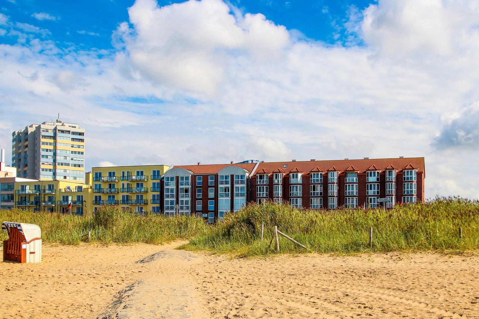 Strand mit Dünen, Ferienhäuser und einem Strandkorb.