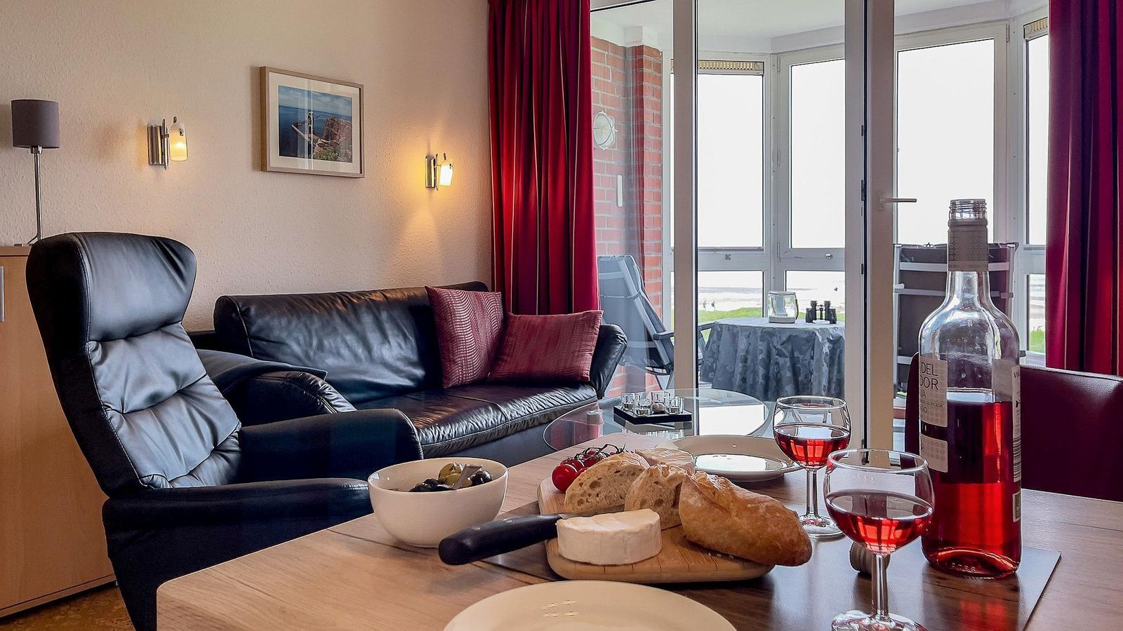Wohnbereich mit Sofa, Stuhl und Tisch mit Wein und Käse.