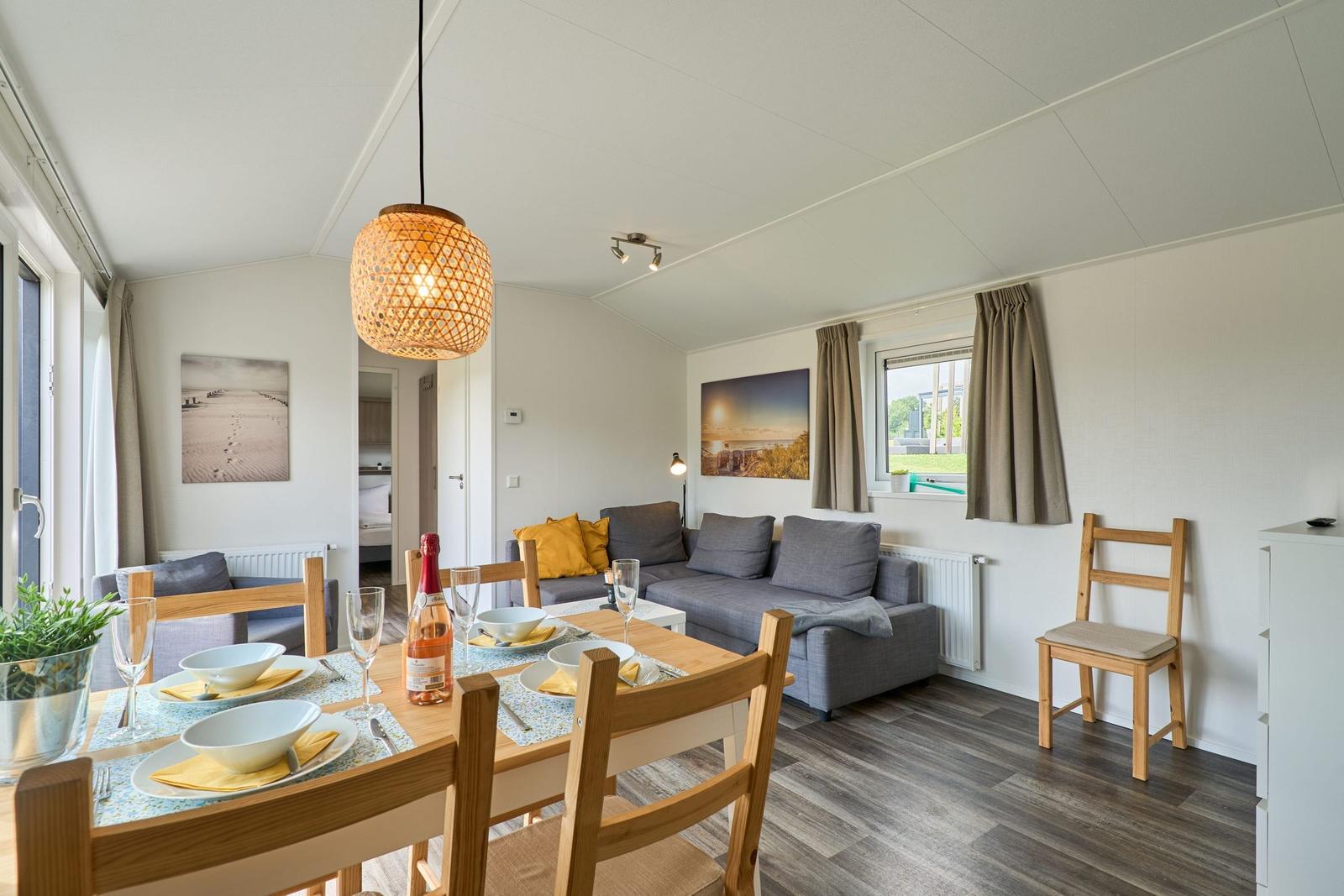 Essbereich mit Tisch und Stühlen, Sofa und Fenster mit Blick nach draußen.