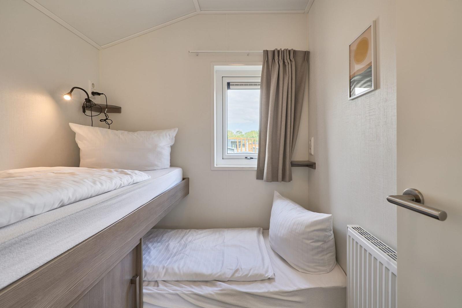 Zimmer mit zwei Betten, Fenster und Wandbild.