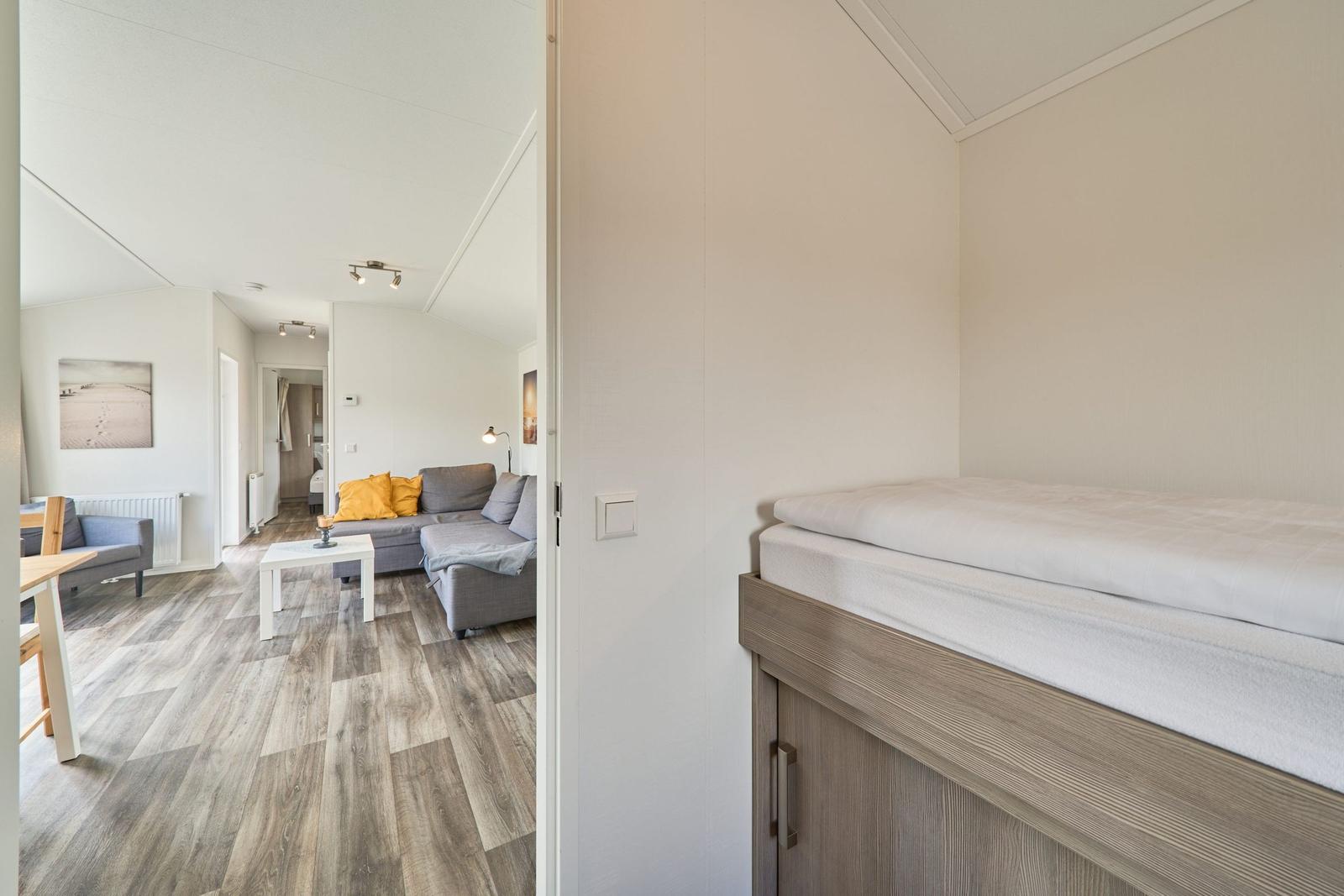 Schlafzimmer mit Bett und Blick in Wohnbereich mit Sofa und Tisch