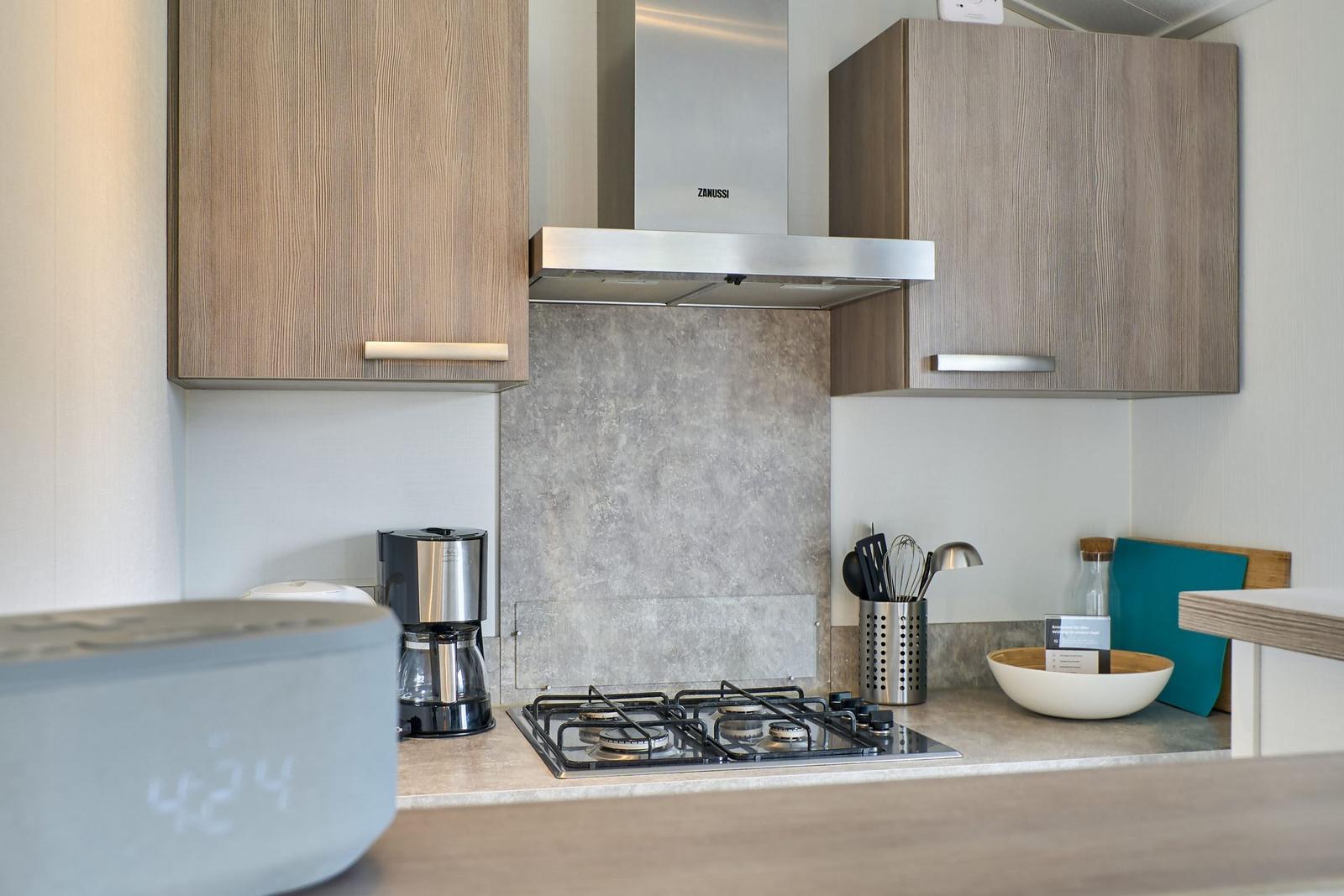 Küche mit Gasherd, Dunstabzug und Holzschränken.