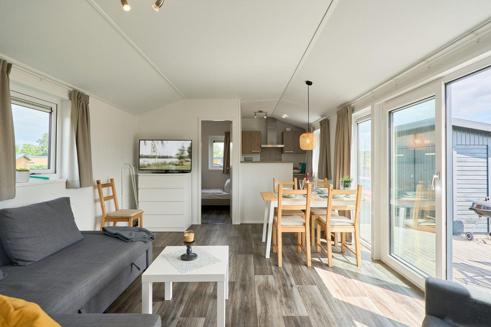 Wohnbereich mit Sofa, Esstisch und Schlafzimmer im Hintergrund.