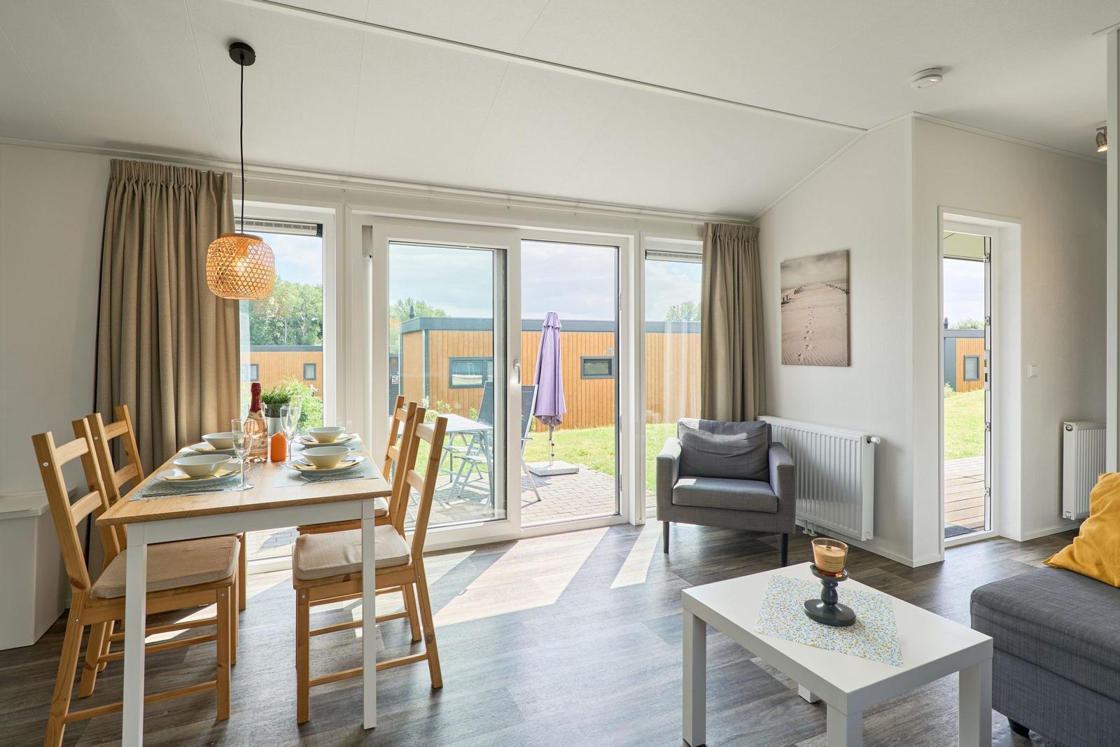 Esszimmer mit Tisch und Stühlen, Blick auf Terrasse mit Garten.