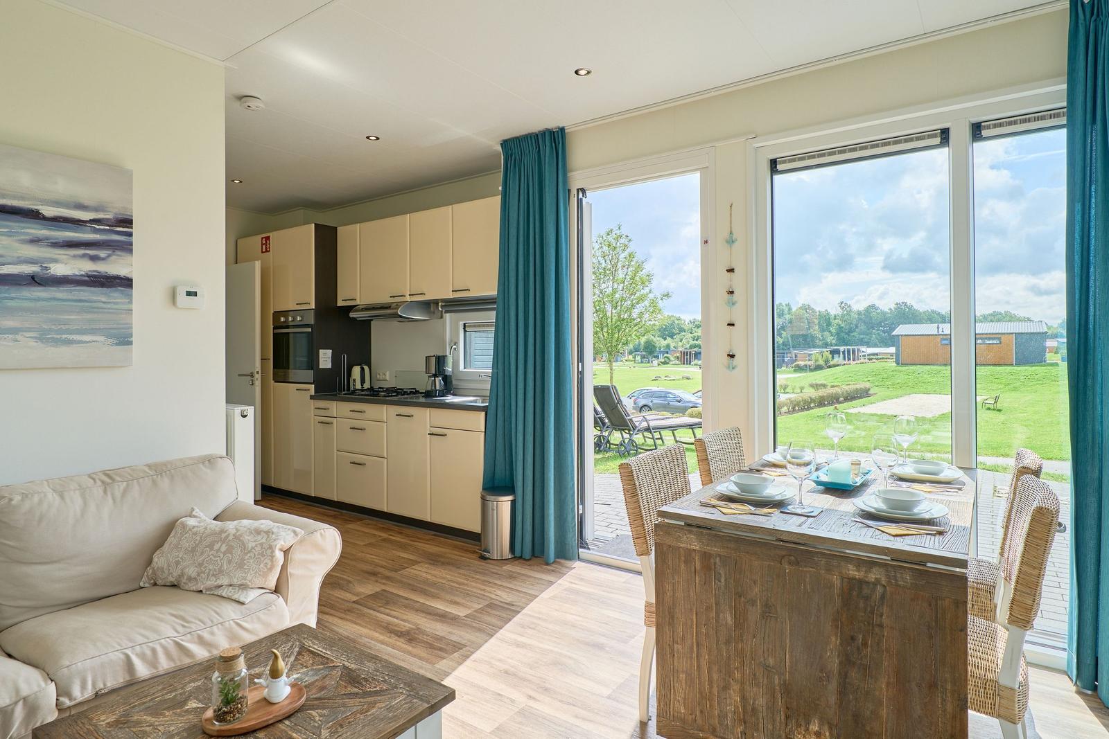 Wohnküche mit Essbereich, großes Fenster und Blick auf Grünfläche.