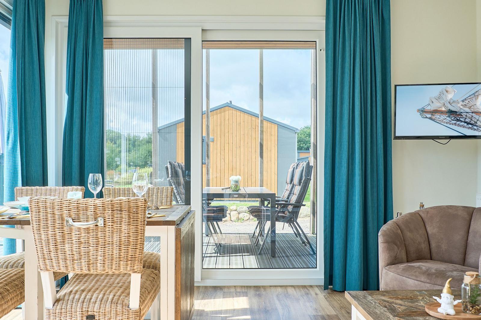 Essbereich mit Blick auf Terrasse und Garten. Sofa und Fernseher im Wohnbereich.