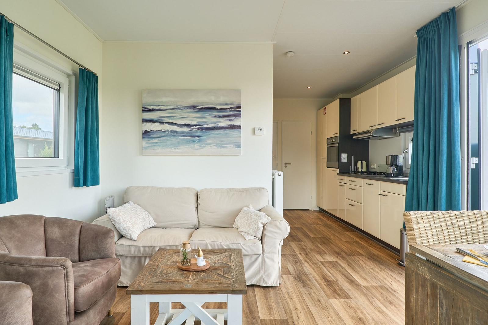 Wohnbereich mit Sofa, Couchtisch und Küche im Hintergrund.