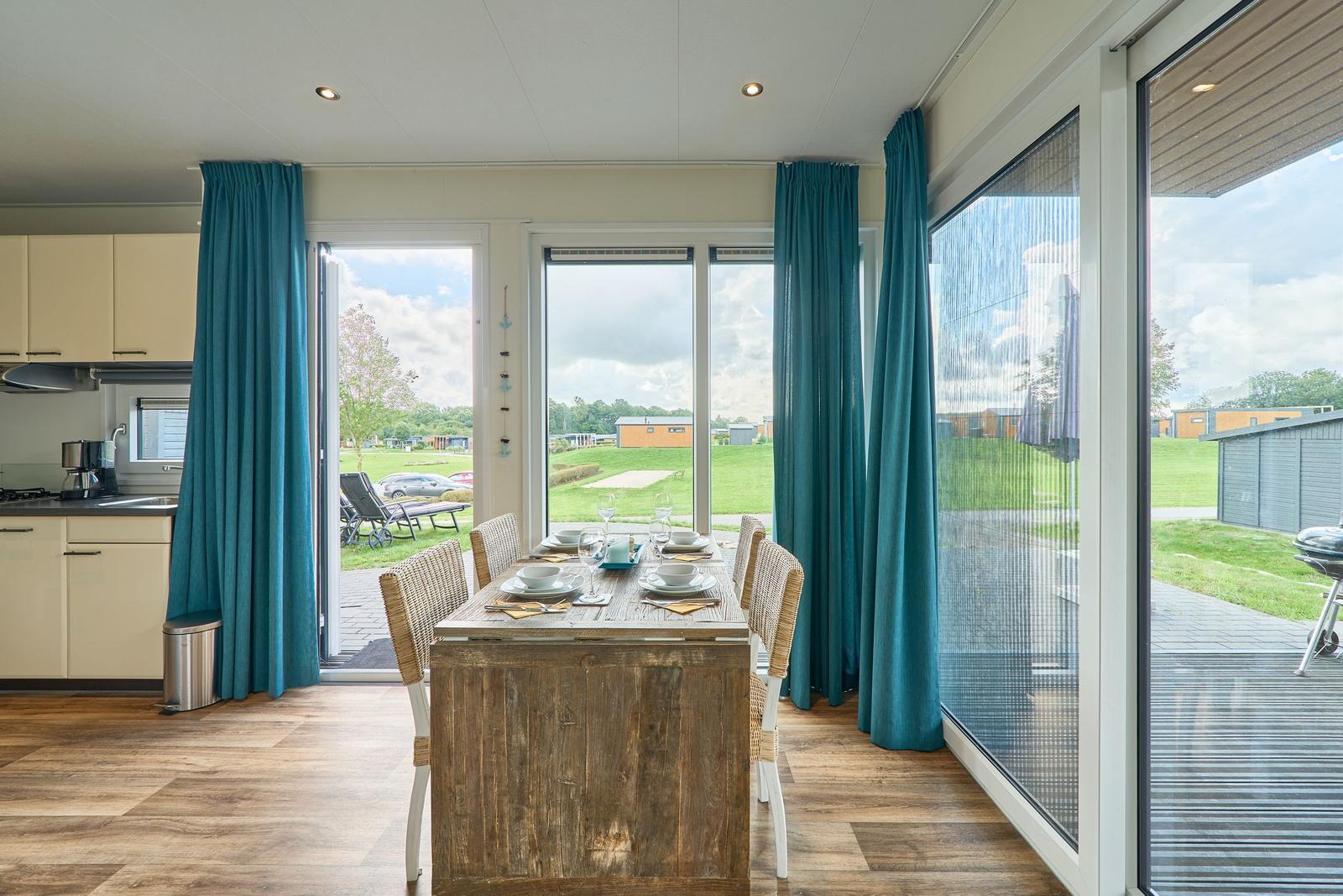 Essbereich mit Tisch und Stühlen, Blick auf Terrasse und Grünflächen.