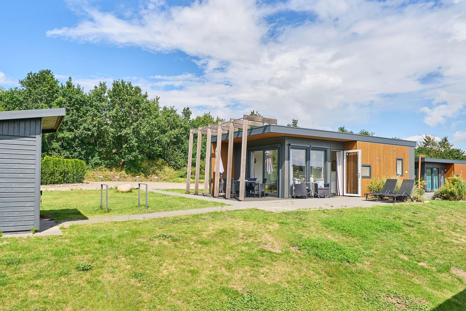 Moderne Ferienwohnung mit Terrasse, Garten und Sitzgelegenheiten unter freiem Himmel.