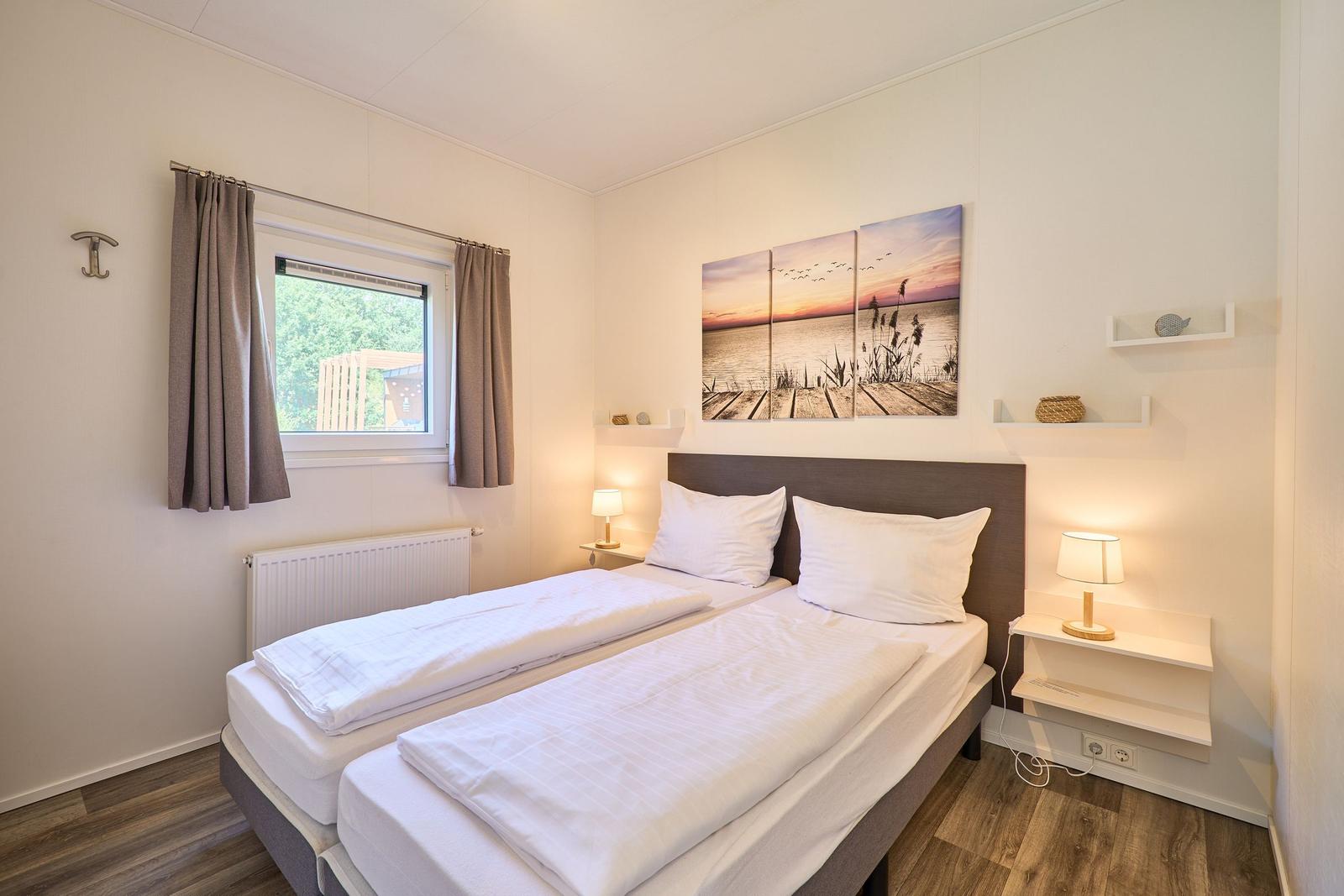 Zwei Einzelbetten mit weißen Bettwäschen, Wandbild und Nachttische mit Lampen.