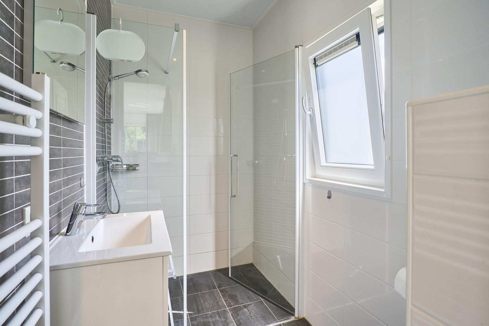 Badezimmer mit Dusche, Waschbecken und Fenster