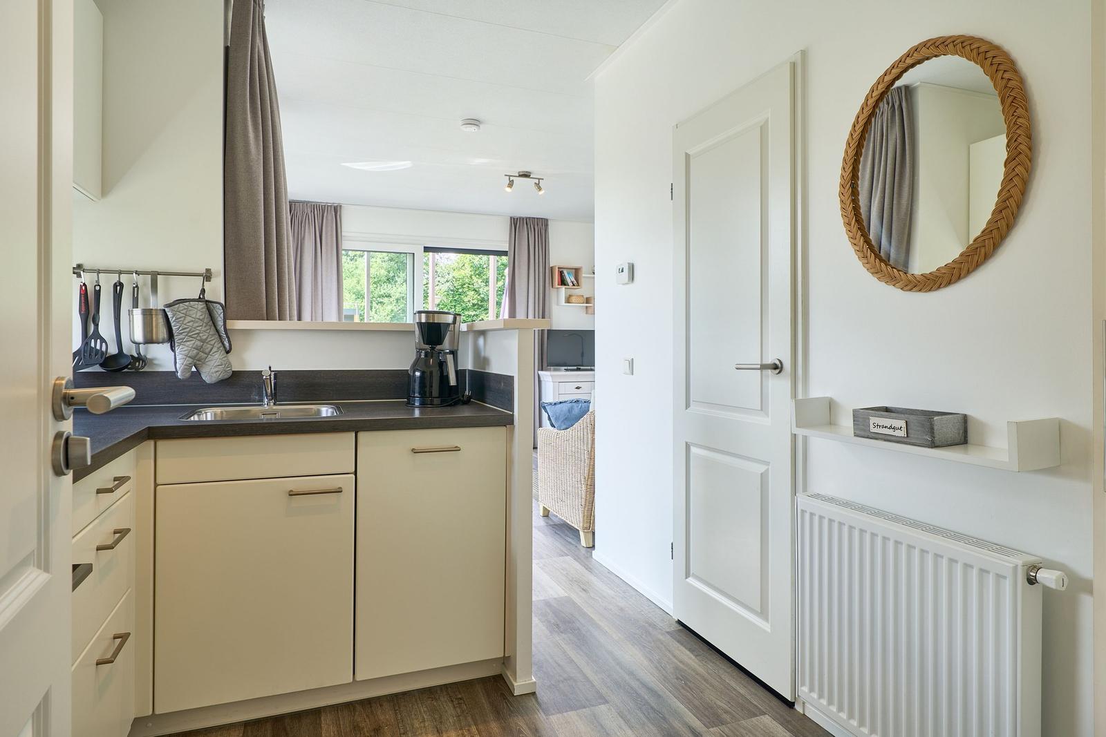 Küche mit Spüle, Kaffeemaschine und Blick in Wohnbereich.