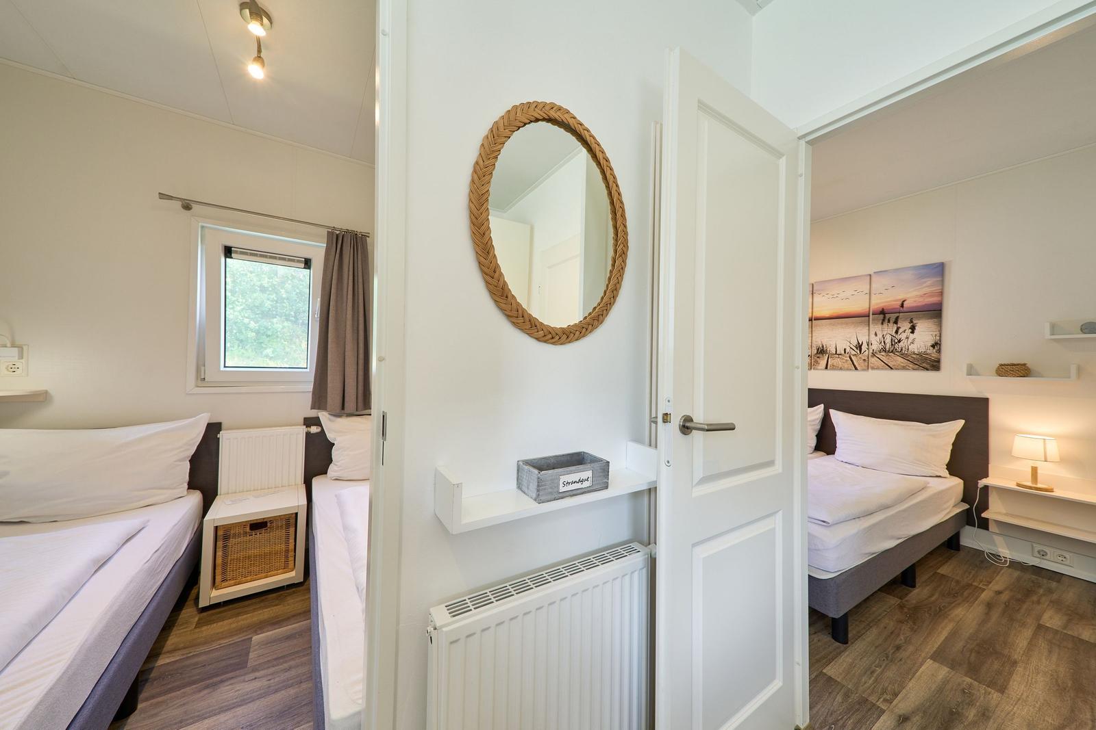 Zwei Schlafzimmer mit Betten, Fenster und Wandspiegel