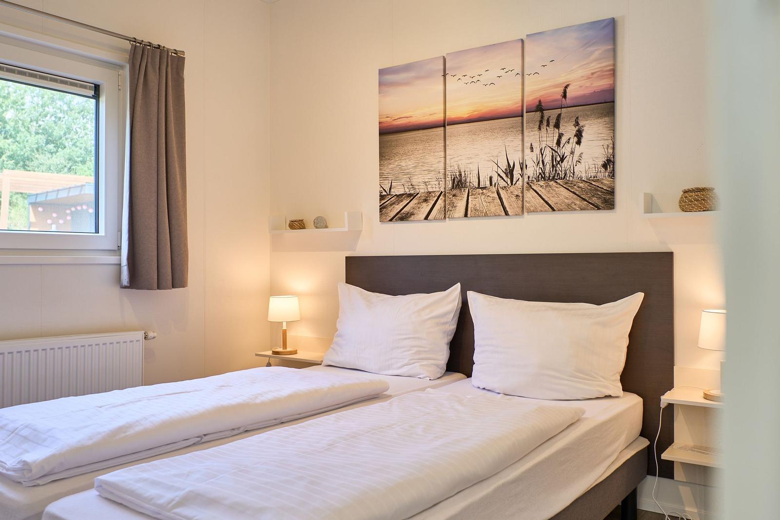 Zwei Einzelbetten mit weißen Bettwäschen und Wandbildern über dem Kopfteil.