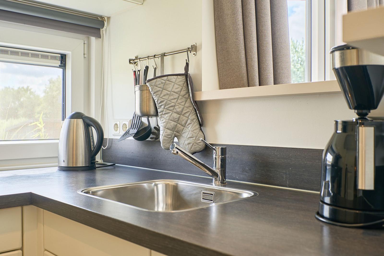 Küchenzeile mit Spüle, Kaffeemaschine und Wasserkocher.