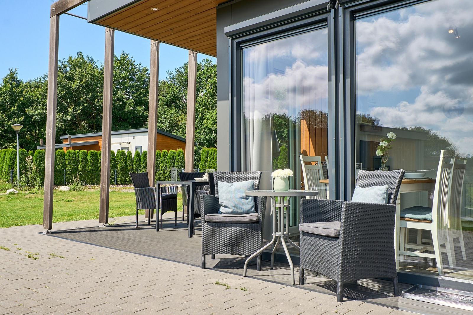 Terrasse mit Sitzgelegenheiten und Blick auf grünen Garten.