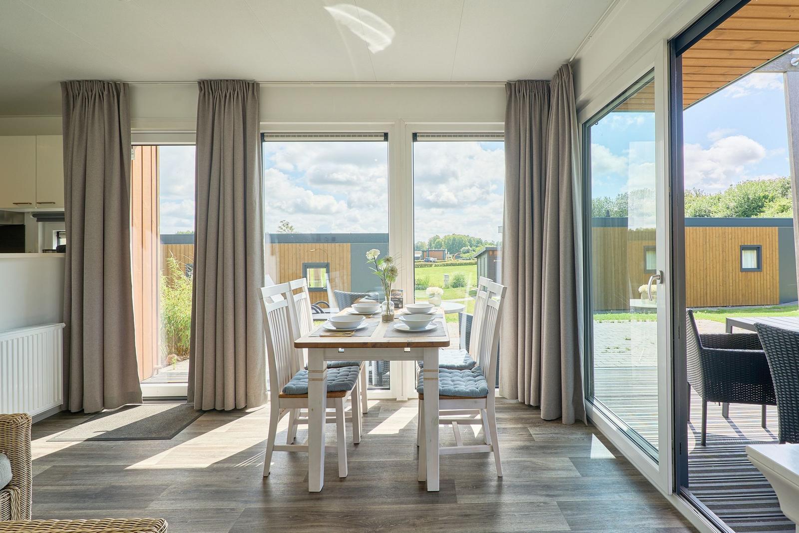 Essbereich mit Tisch und Stühlen, großzügige Fensterfront mit Blick auf Garten und Terrasse.