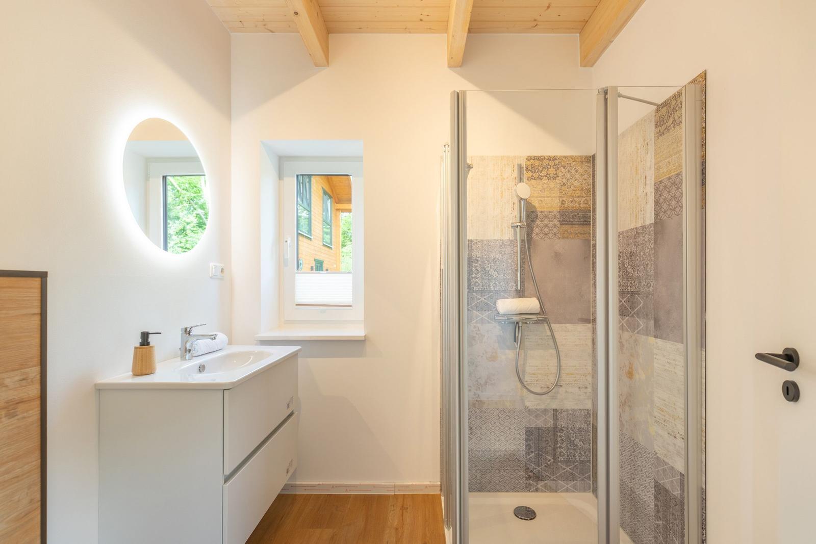 Badezimmer mit Dusche, Waschbecken und Fenster