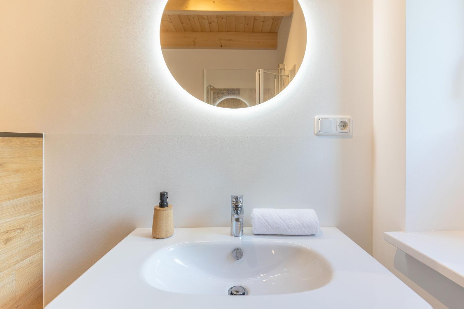 Waschbecken mit runder beleuchteter Spiegelfläche und Handtuch