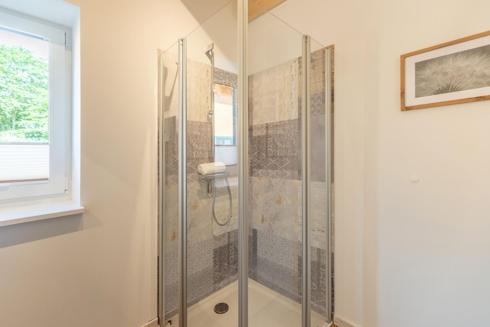 Duschbad mit Glaswand, Fenster und Wandbild.