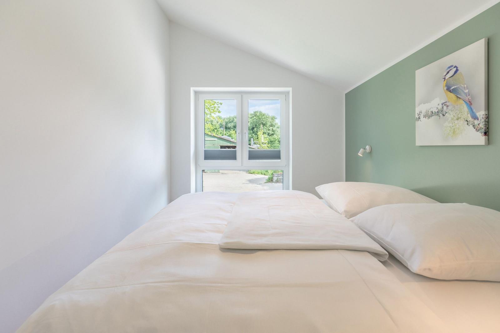 Schlafzimmer mit Bett, Fenster und Wandbild