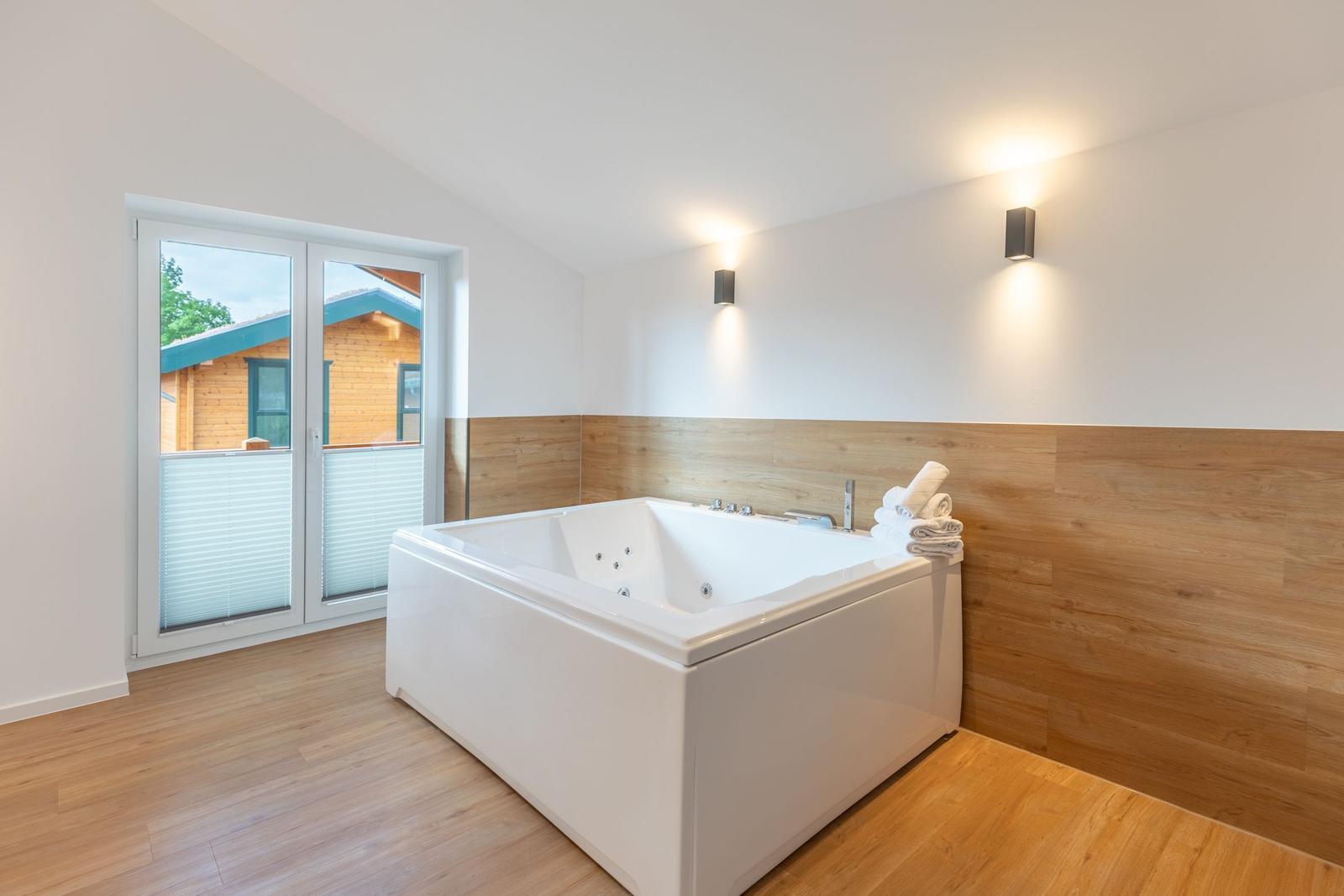 Bad mit Whirlpool, Holzwand und Fenster zur Terrasse.