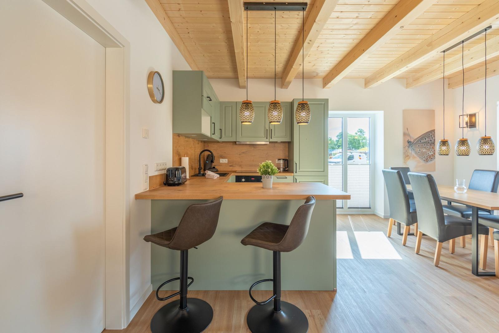 Küche mit Essbereich, Holzbalkendecke und modernen Hängelampen.