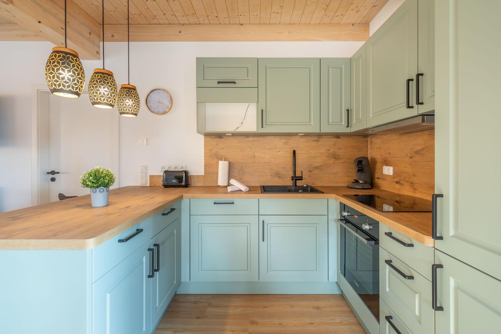 Küche mit Holzoberflächen, hellen Schränken und moderner Ausstattung.