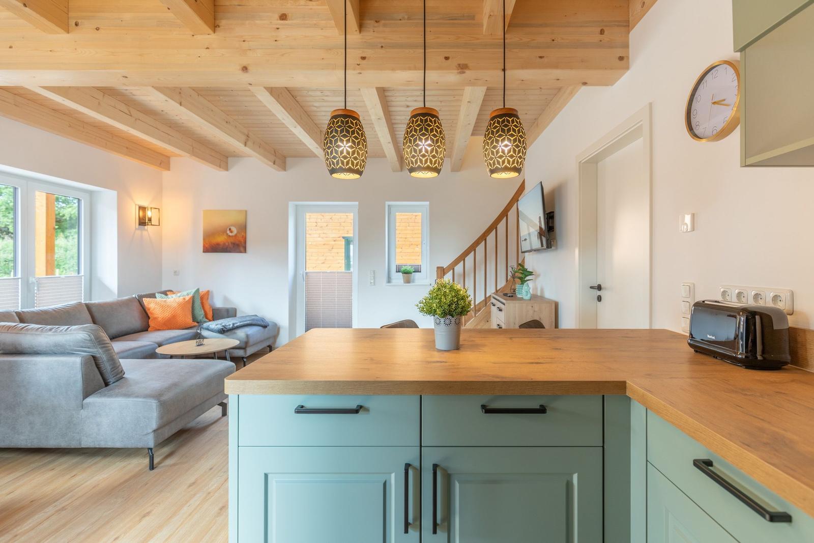 Küche mit Holzwerkzeug und Wohnbereich mit Sofa und Treppenhaus.