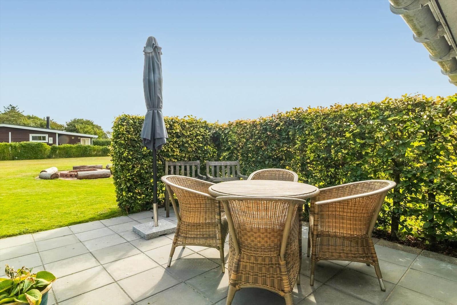 Terrace with table, four chairs, and closed umbrella.