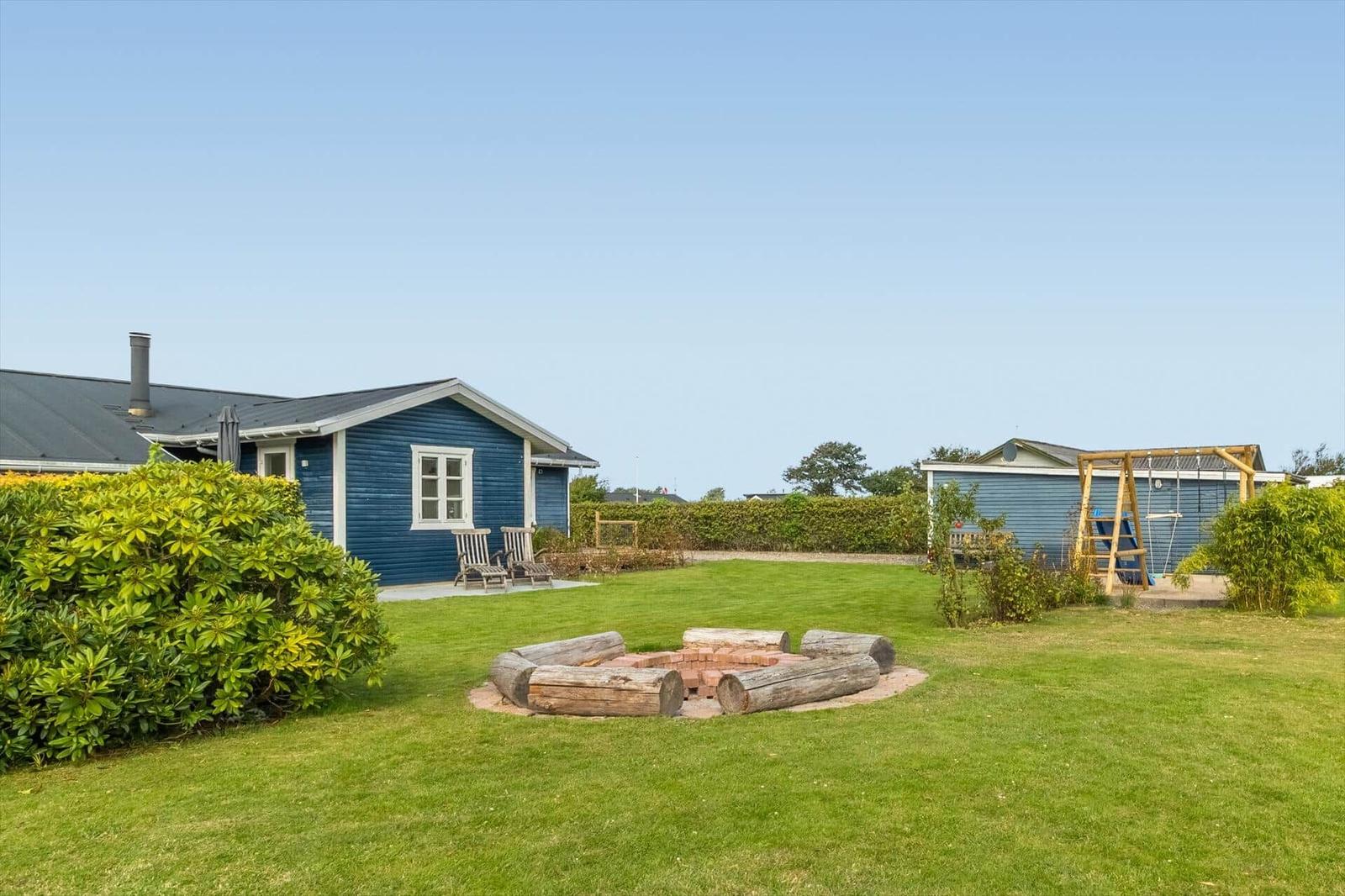 Blue wooden house with garden, fire pit, and playground