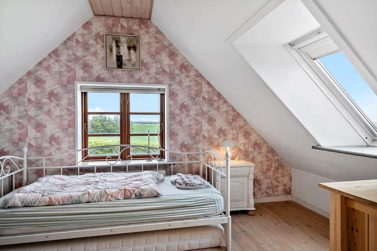 Bedroom with sloped ceilings, window, and skylight.