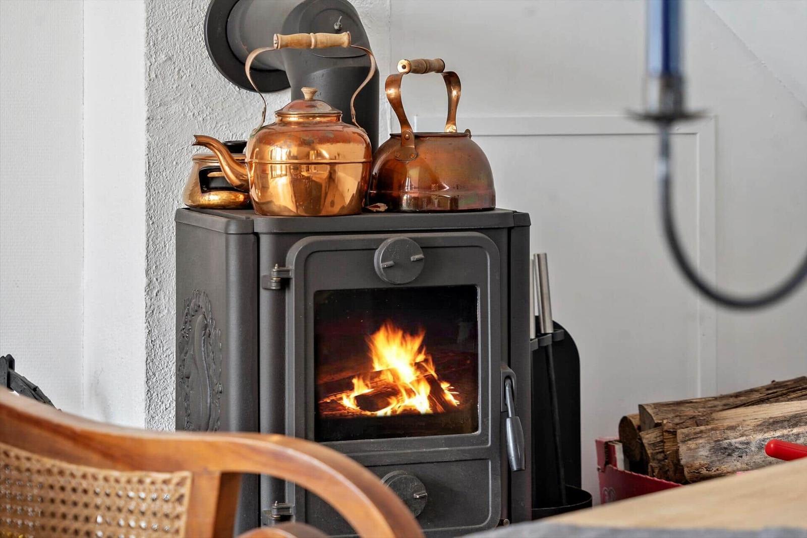Wood stove with burning fire and copper kettles on top.