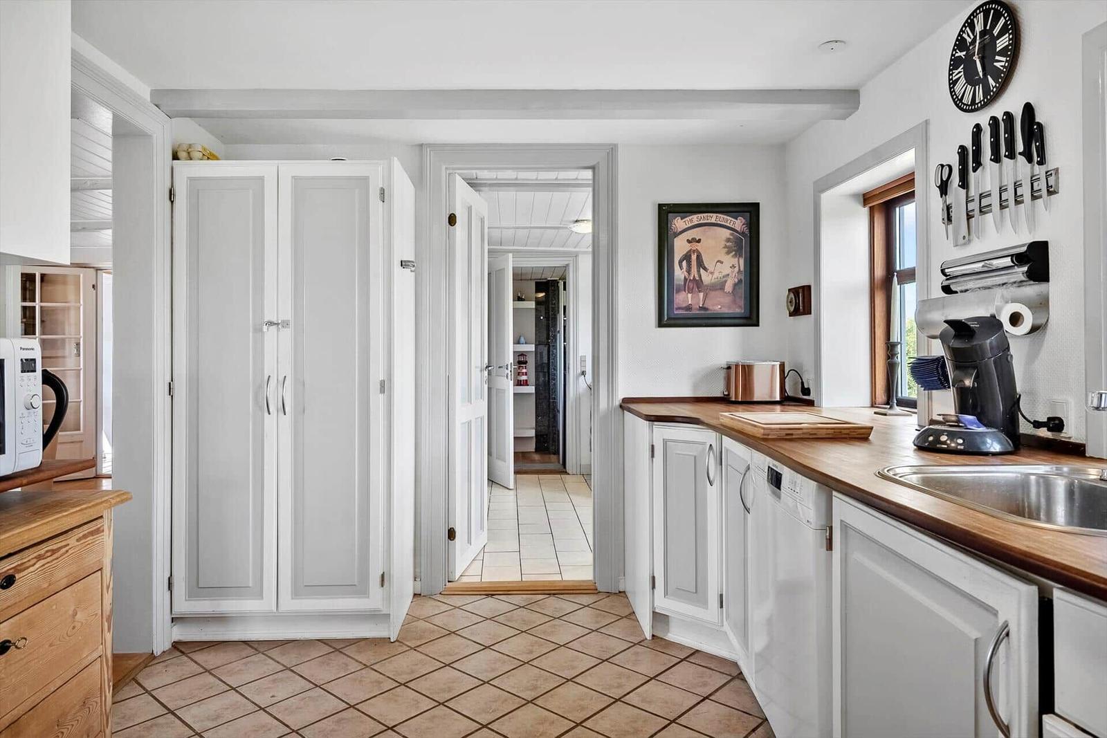 Kitchen with wooden surfaces, white cabinets, and view into adjacent rooms.