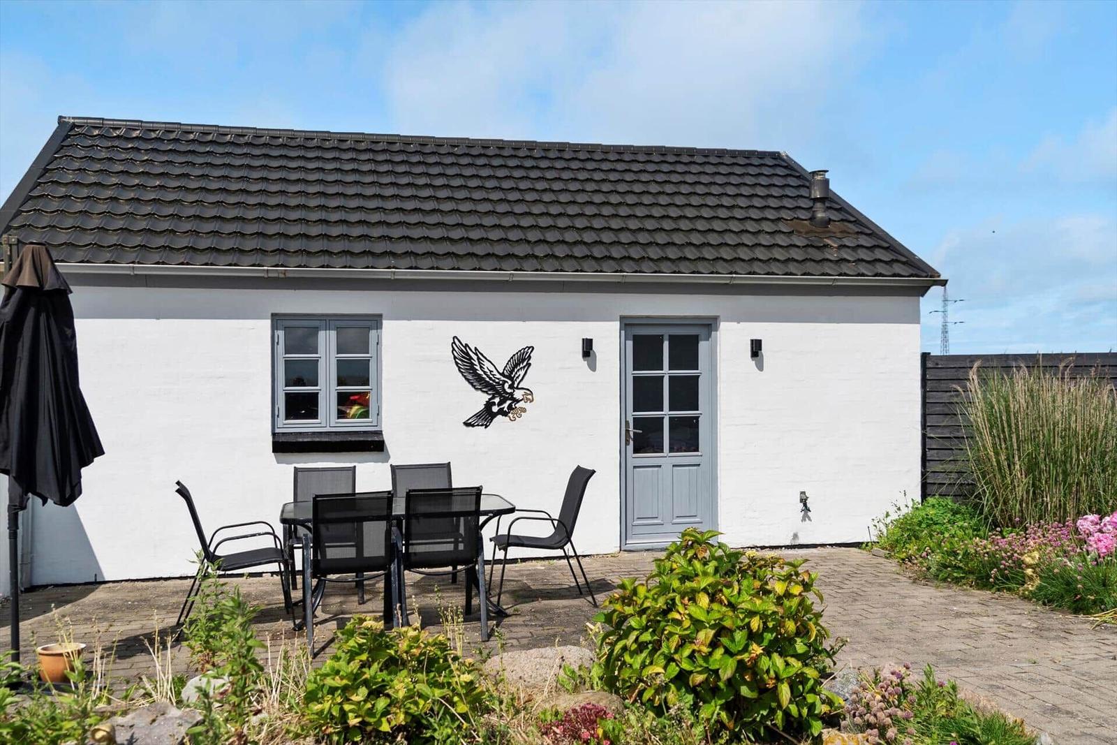 White vacation home with terrace, garden, and bird decor on the facade.