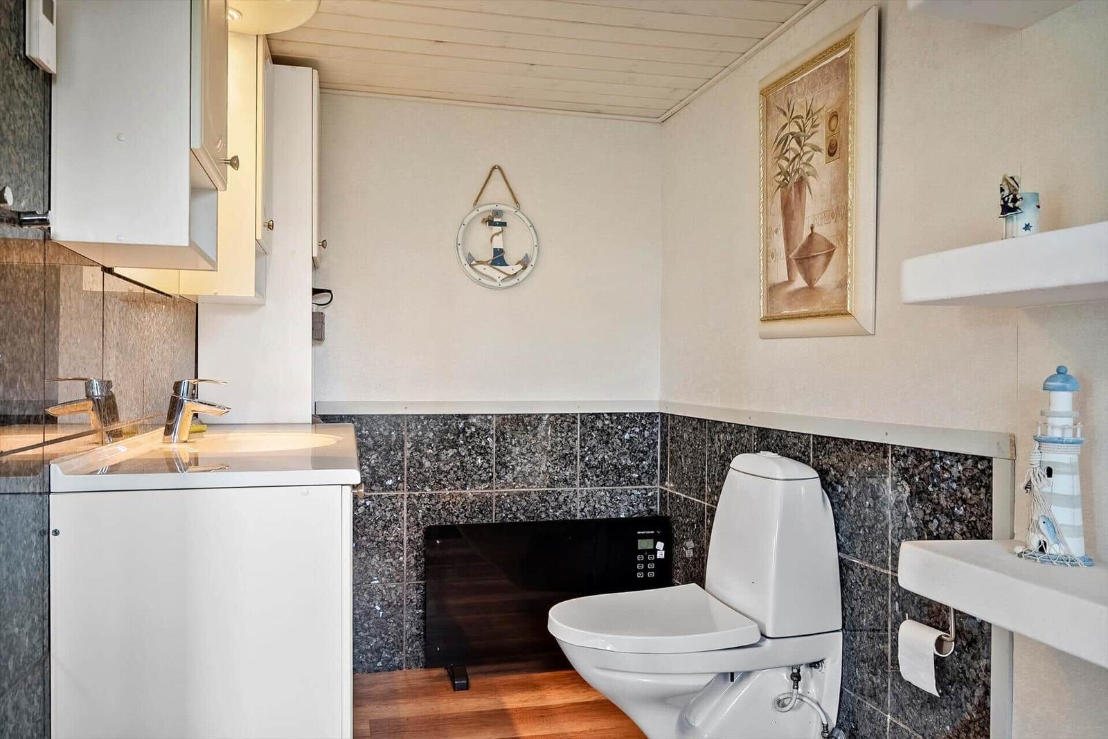 Bathroom with toilet, sink, and nautical decor.