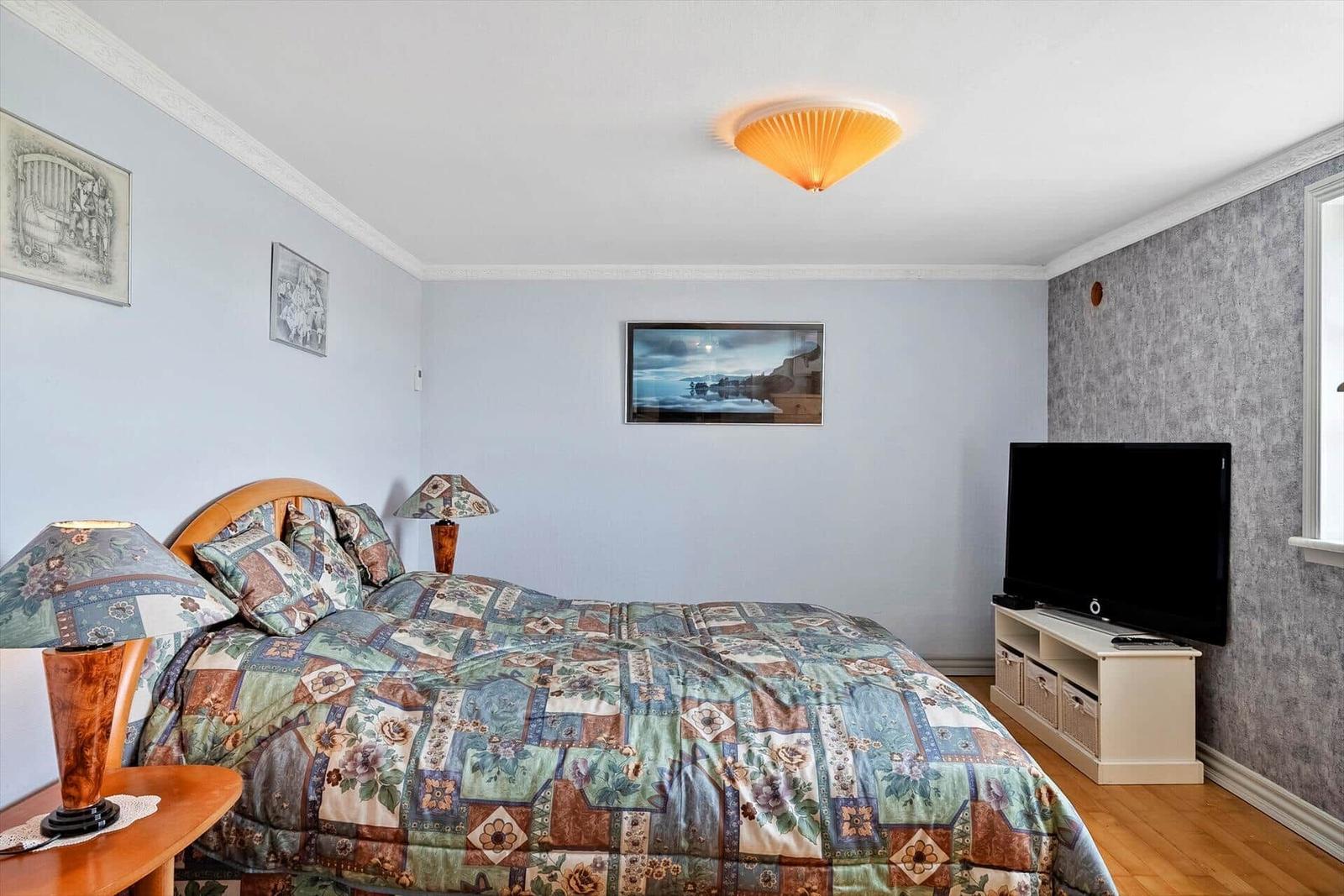 Bedroom with bed, TV, and wall art.