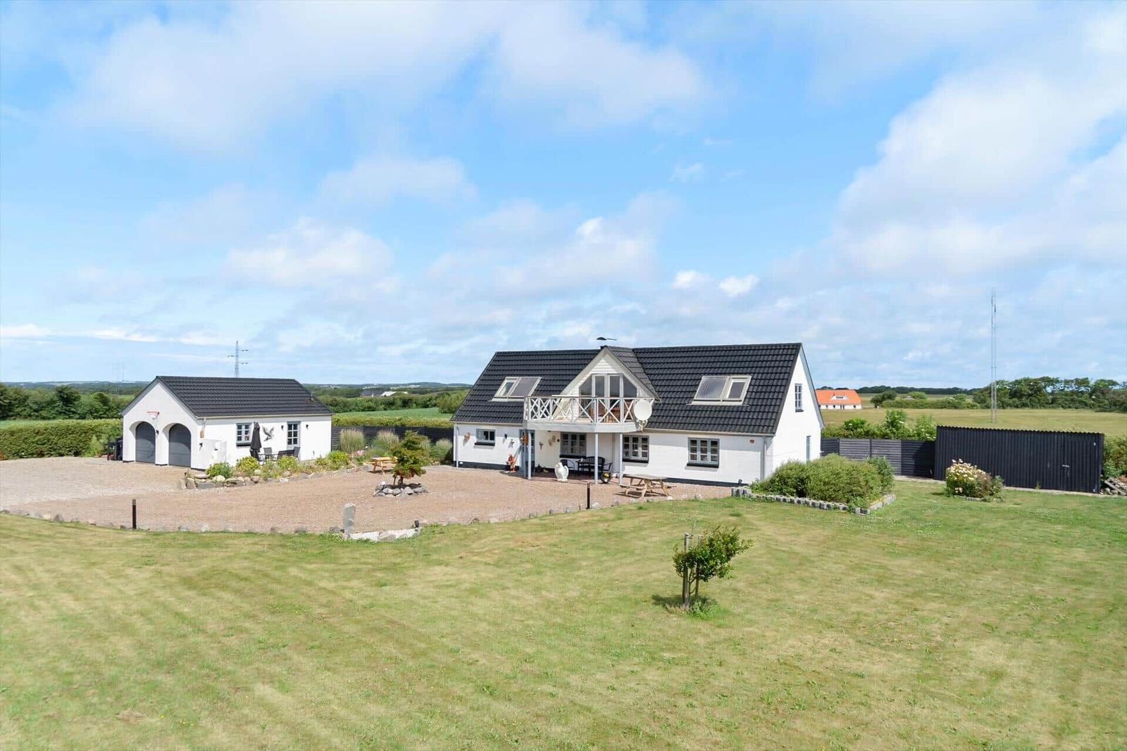 White holiday home with terrace and garden. Attached garage building.