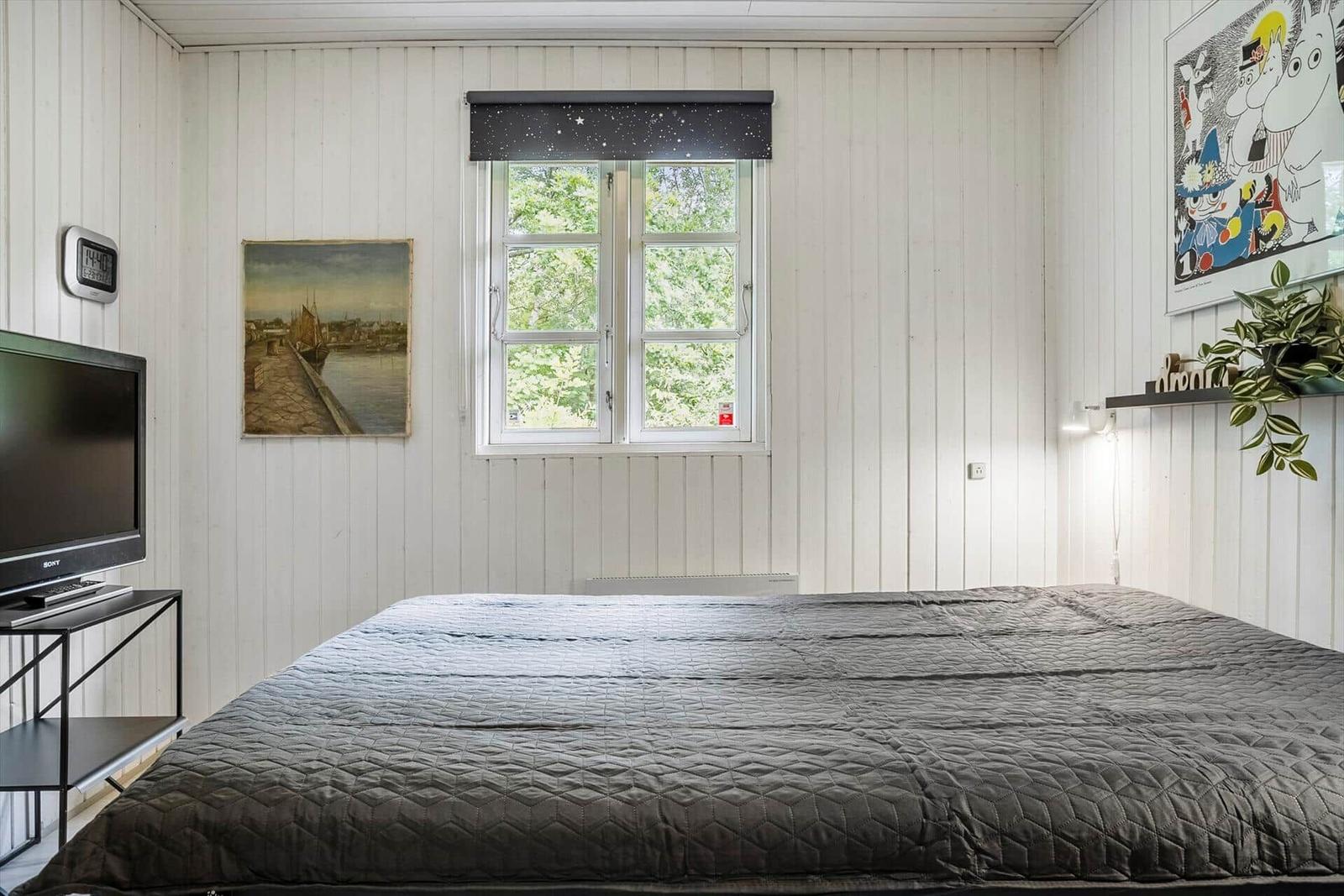 Bedroom with bed, window, and wall pictures.