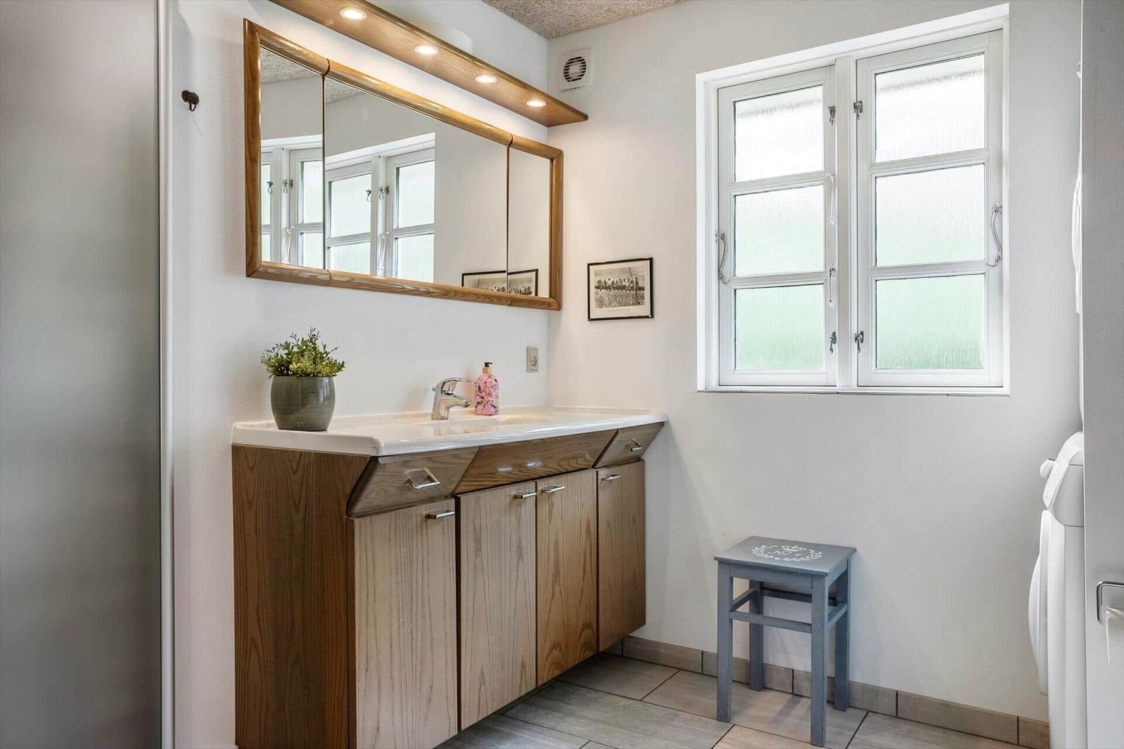 Bathroom with wooden vanity, mirror, and window