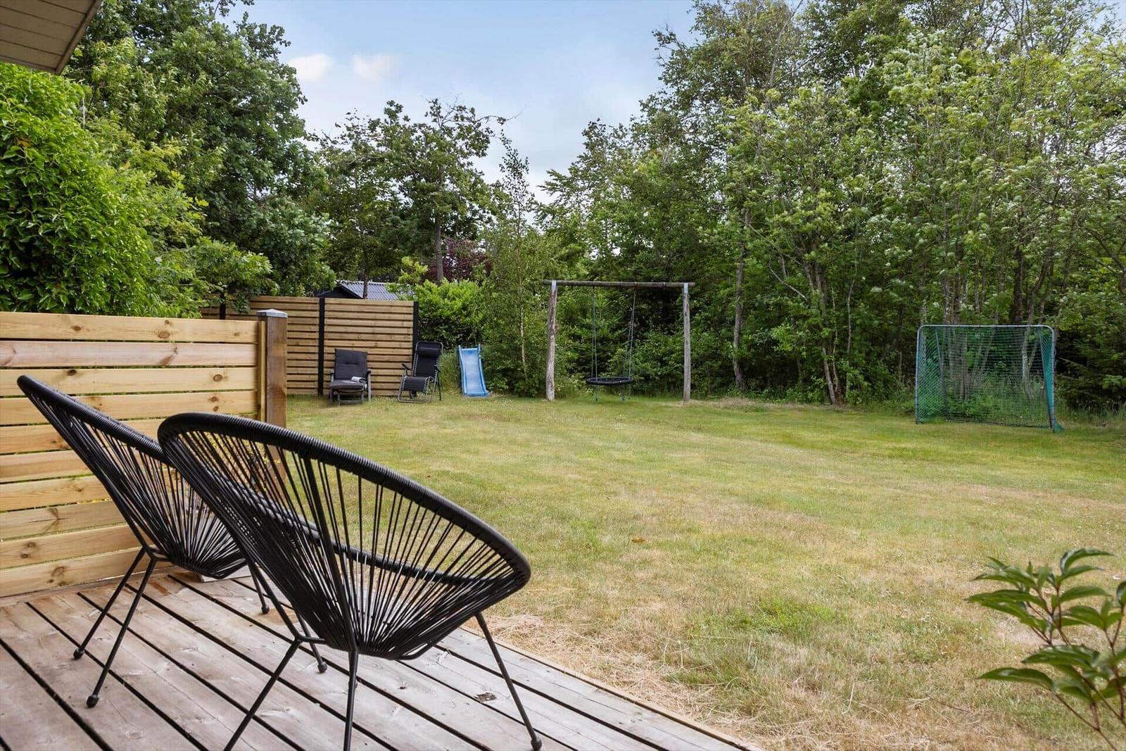 Backyard with wooden deck, swing, slide, and soccer goal.
